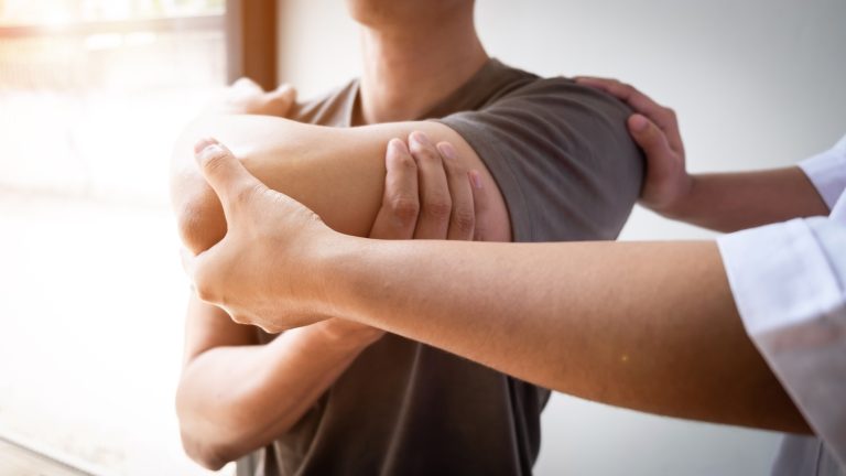 Therapist treating a male injured by rotator cuff stretching method